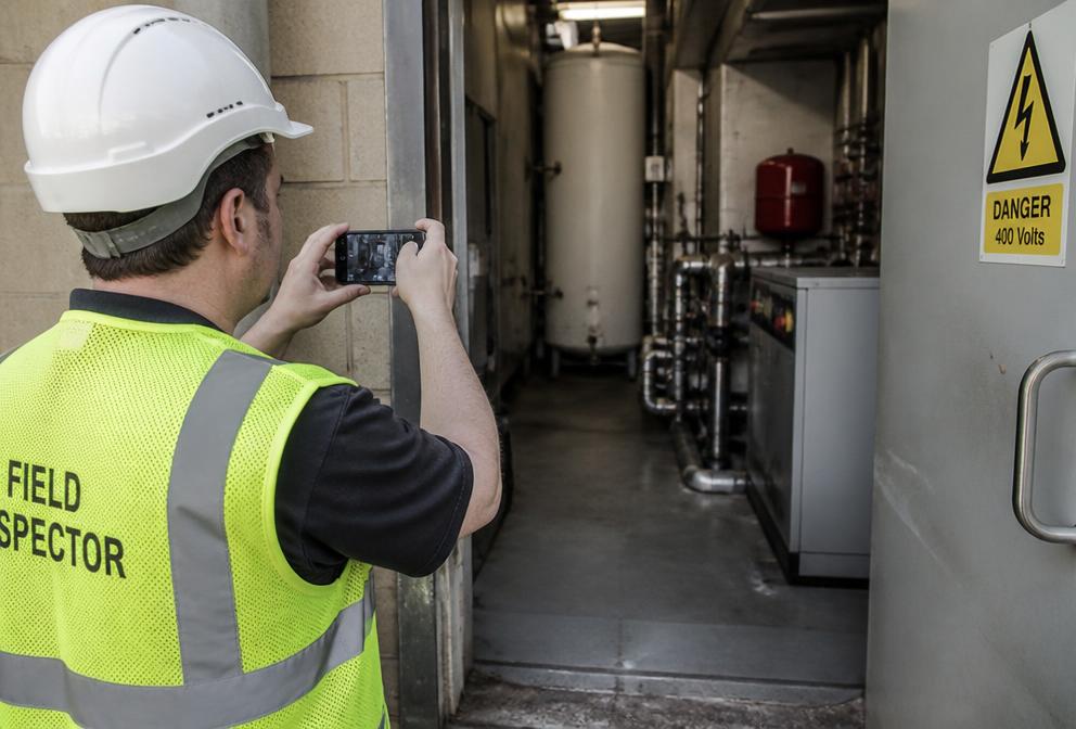 Field inspector filming a plant room with a smartphone